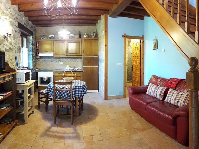 Interior de uno de los apartamentos, con escalera de madera, sofá y mesa.