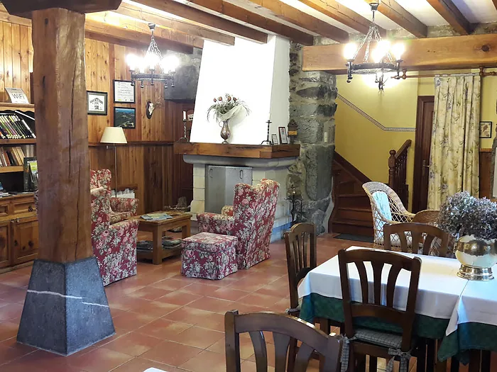 La sala de estar del caserío, con vigas de madera, chimenea y butacas.