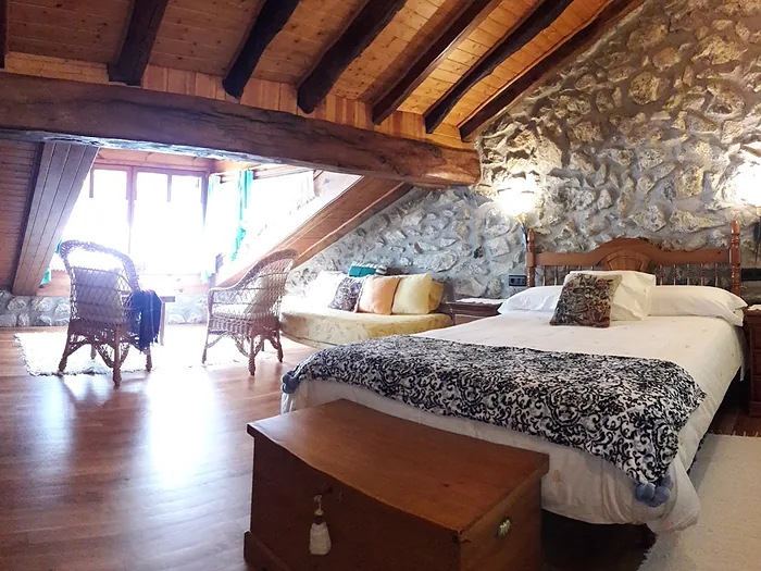 Habitación bajo el tejado, con viga de madera vista y pared de piedra.