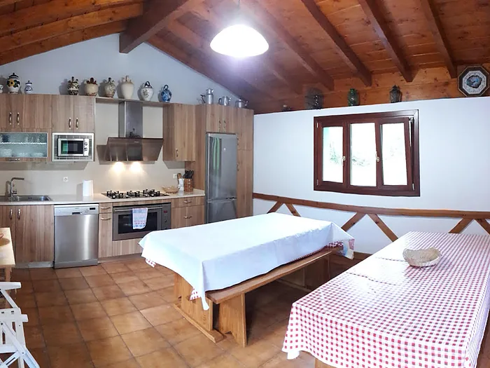 El txoko de fuera, con mesa larga vestida y la cocina al fondo.